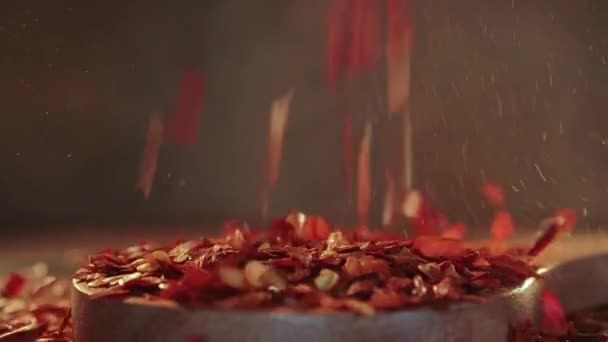 キッチンテーブルの上に木製のスプーンクローズアップで赤唐辛子のフレーク — ストック動画
