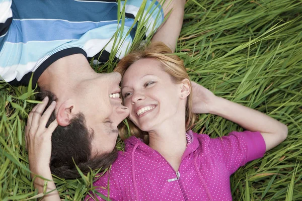 Jovem casal amoroso deitado na grama verde — Fotografia de Stock