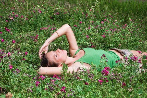Όμορφη νεαρή κοπέλα ξαπλωμένη στο πράσινο γρασίδι Royalty Free Φωτογραφίες Αρχείου