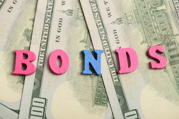 Word bonds at wooden letters on US Dollar bills