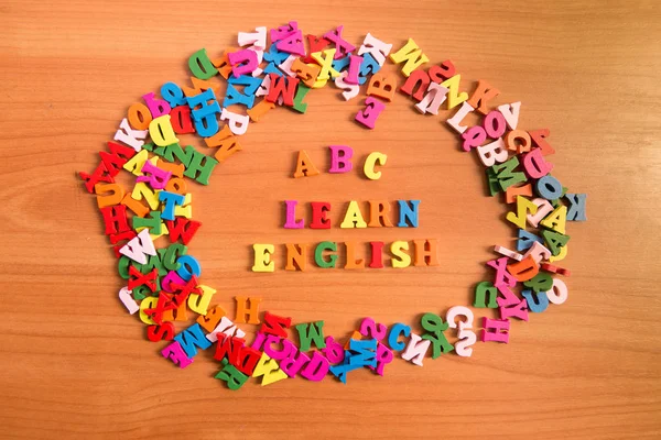 ABC LEARN ENGLISH wooden letters around a pile of other letters over table board surface