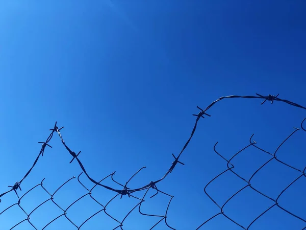Fond d'une clôture barbelée contre un ciel bleu — Photo