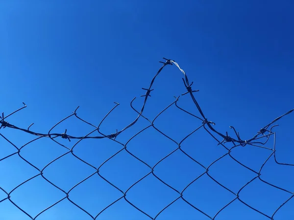 Fond d'une clôture barbelée contre un ciel bleu — Photo