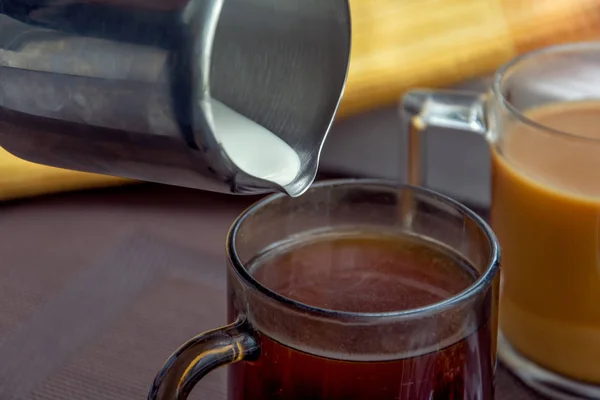 Две чашки кофе. Выливать молоко в чашку кофе . — стоковое фото
