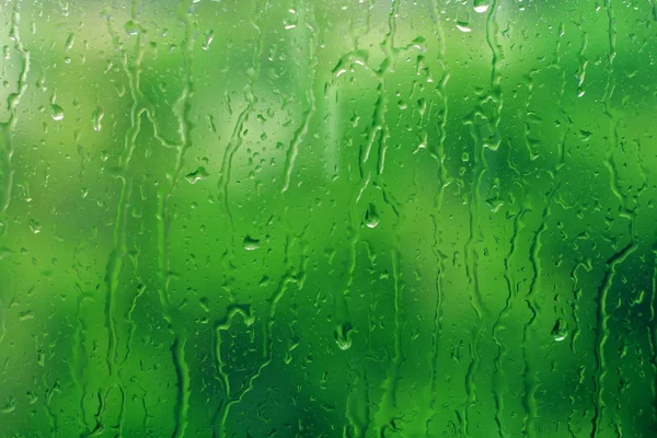 Arka plan olarak yeşil ağaç ile pencereye yağmur düşer. Doğal su cam üzerine düşer. Seçici odaklama — Stok fotoğraf
