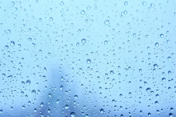 Lluvia cae en la ventana. Gotas de agua natural sobre vidrio. Enfoque selectivo — Foto de Stock