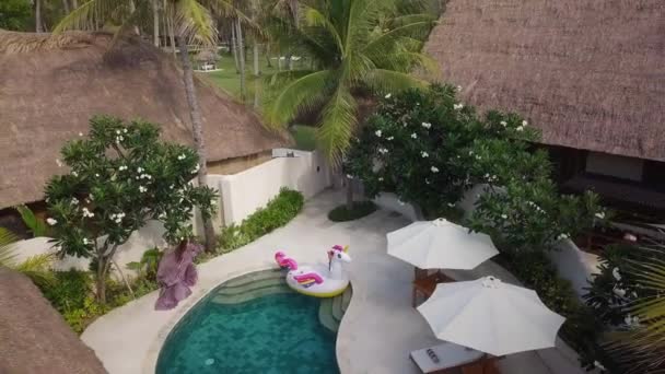 Woman in beautiful dress is passing in private tropical villa hotel near pool, aerial view. — Stock Footage Woman in beautiful dress is passing in private tropical villa hotel near pool, aerial view. Royalty Free Stock Video