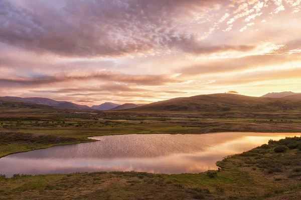 Summer landscape in the tundra with a lake in the mountains in sunrise