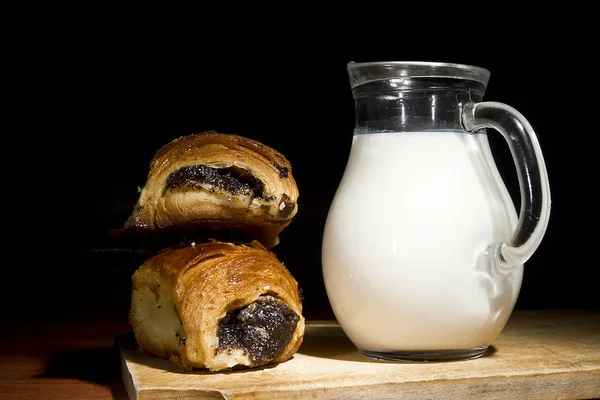 Sweet baking in a wooden plate and milk in a glass bowl