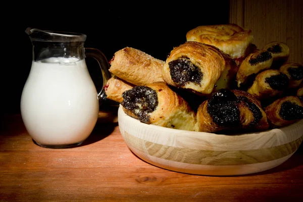 Sweet baking in a wooden plate and milk in a glass bowl