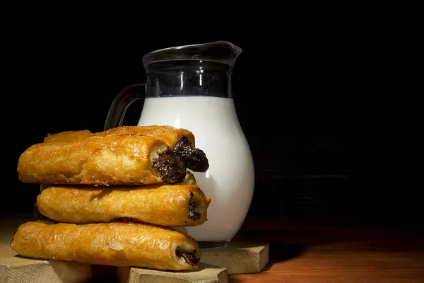 Sweet baking in a wooden plate and milk in a glass bowl