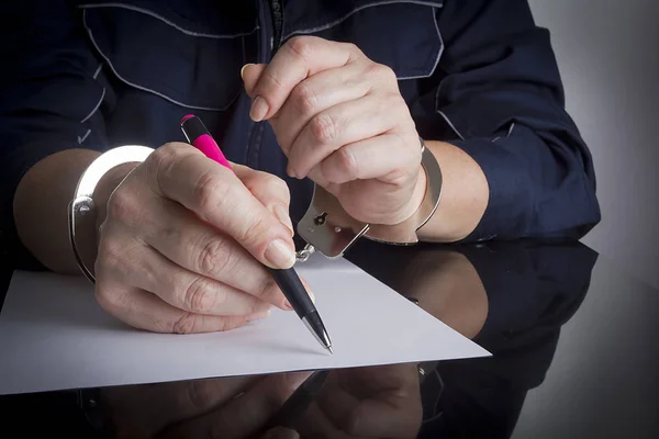 Vrouwelijke handen in handboeien schrijven — Stockfoto