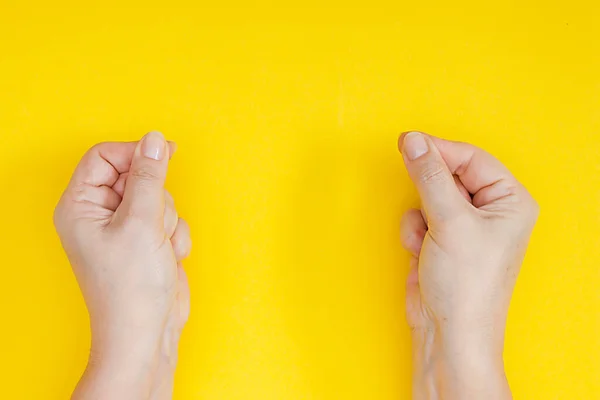黄色の背景にピンチで握りしめ指で手 — ストック写真