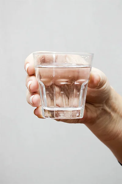 Mão Com Vidro Água Sobre Fundo Cinza — Fotografia de Stock