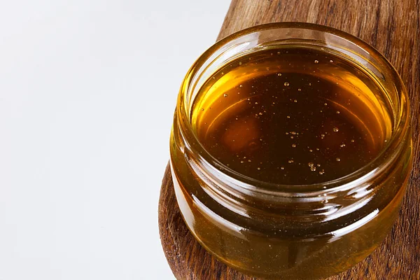 在木制切菜板上的玻璃碗里放新鲜蜂蜜 — 图库照片