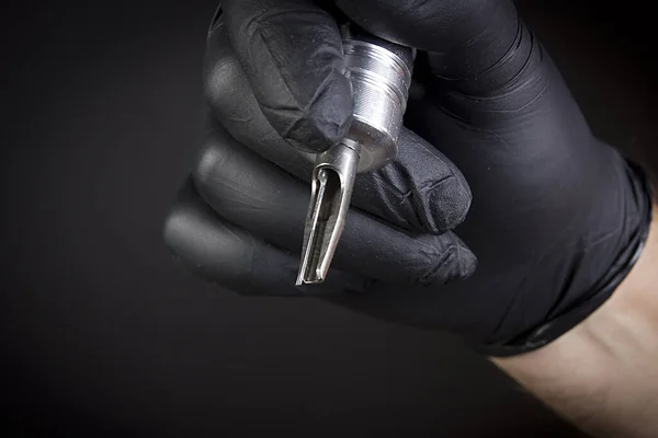 Tattoo tool in a man\'s hand in a black glove