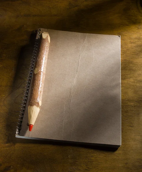 桌上有红色铅笔及记事本的大型木制铅笔 — 图库照片