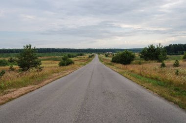 Düz asfalt yol alanları ve çayırlar, yaz günü