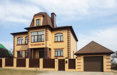 Beautiful suburban two-storeyed yellow brick house with garage clipart