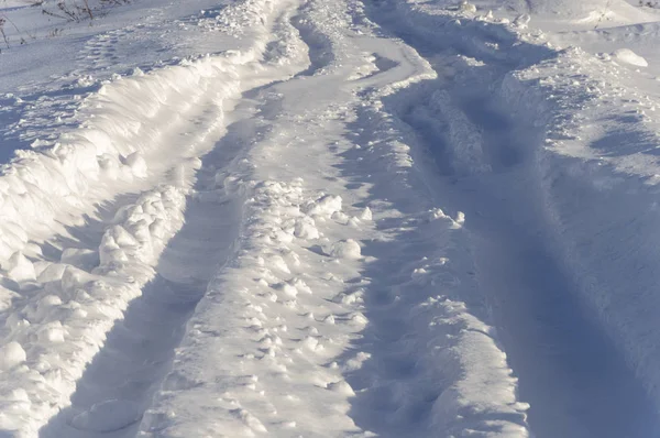 道路は雪で覆われています 深い雪の中でトラックをタイヤします 晴れた冬の日 — ストック写真
