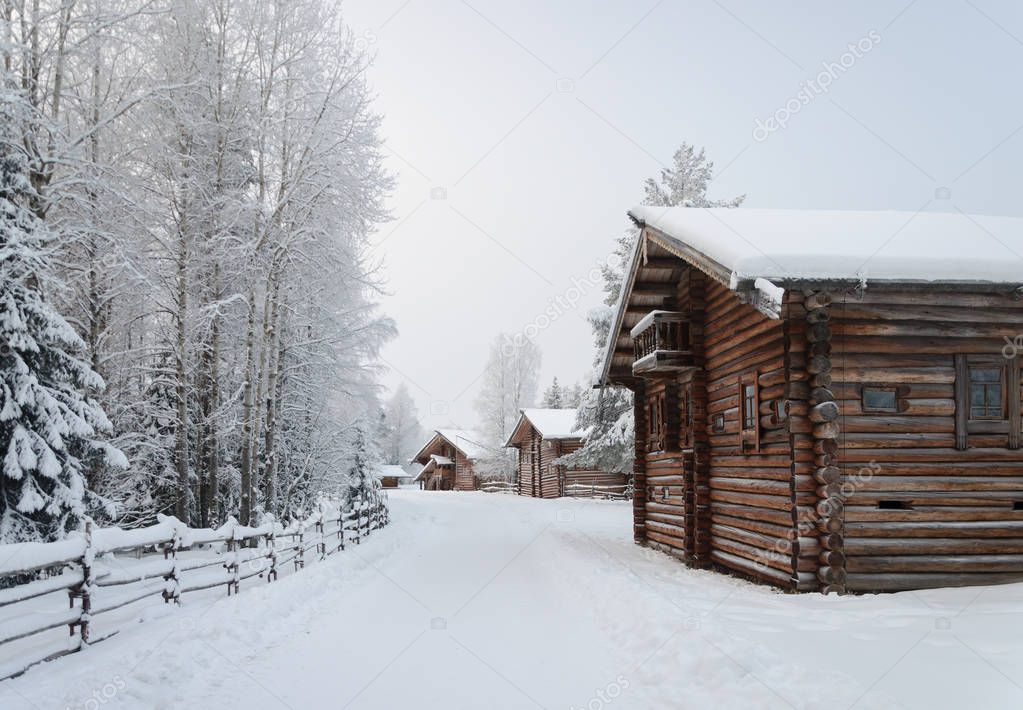 Old wooden country houses, covered with snow in northern open air museum Malye Korely near Arkhanglesk, Russia. Frosty winter day.
