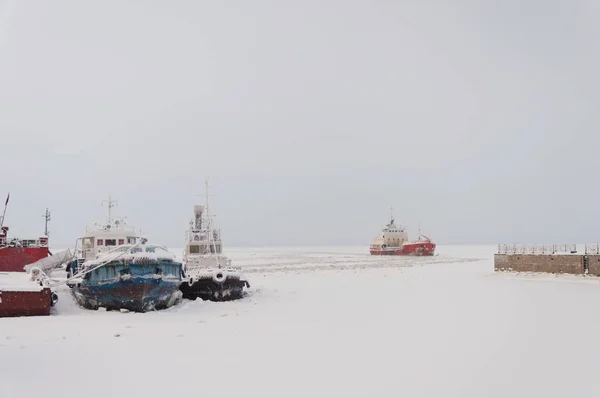 Ships at the pier among the ice on the Northern Dvina river in Arkhangelsk, North Russia. Winter frosty day.