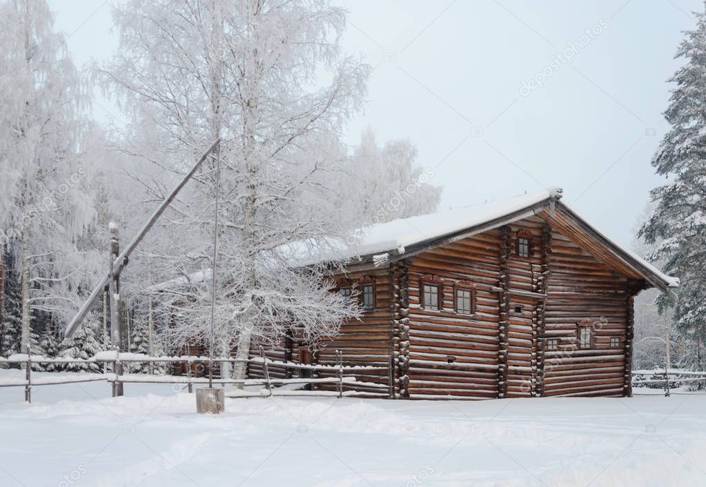 Old wooden house with shadoof in Northern Russian village. Open air museum Malye Korely near Arkhanglesk, Russia. Frosty winter day.