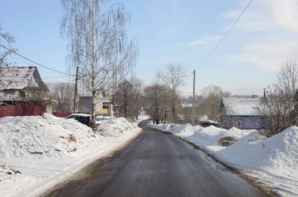 Route asphaltée humide avec des dérives de neige sur les côtés — Photo