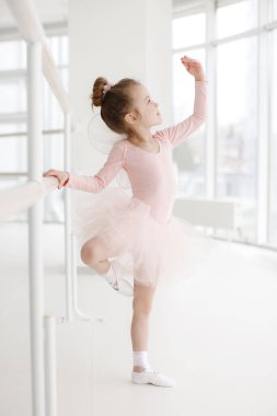 Bale stüdyosu sınıfında küçük şirin kız. Pembe tutu, küçük balerin kız. Çok güzel çocuk beyaz bir stüdyoda klasik bale. Çocuk dans. Gerçekleştirme çocuklar. Genç dansçı bir sınıfta yetenekli. Okul öncesi çocuk sanat dersleri