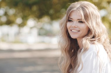 Bir bahar parkta açık havada kıvırcık saçlı güzel bir kadın portresi. Portre hülyalı ve hava çekici kız oynak ve kaygısız güneşli güzel gülümseme ile olmak. Sağlıklı açık havada bir yaşam tarzı. Mutlu kadın portre yaz veya bahar gün ou