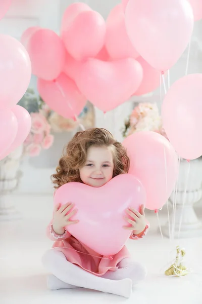 バレンタインの日 ポストカード 金髪巻き毛の小さな女の子は ピンクの風船に囲まれた白いスタジオでポーズします ハートのピンクの風船と白いスタジオで美しい幼児少女 バレンタインの日 誕生日 — ストック写真