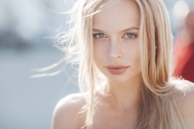 Uzun, güzel bir genç kadınla pink düz saç ve gri gözler, güzel makyaj, dolgun dudaklar, tatlı bir gülümseme, Sarışın, ona vakit şehirde, yaz aylarında açık havada beyaz mayoyu ve güneş ışığında poz kareli gömlek giymiş