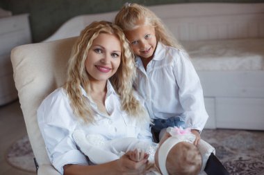 Anne ve bebek birlikte gülümseyen. Seviyorum. Mutlu neşeli aile anne ve iki kızı öpüşme ve evde sarılma. Güzel sağlıklı anne ve küçük kızı. Annelik kavramı. Ebeveynlik. Annelik. Anne ve çocuklar eğlenmek ve birlikte oynama