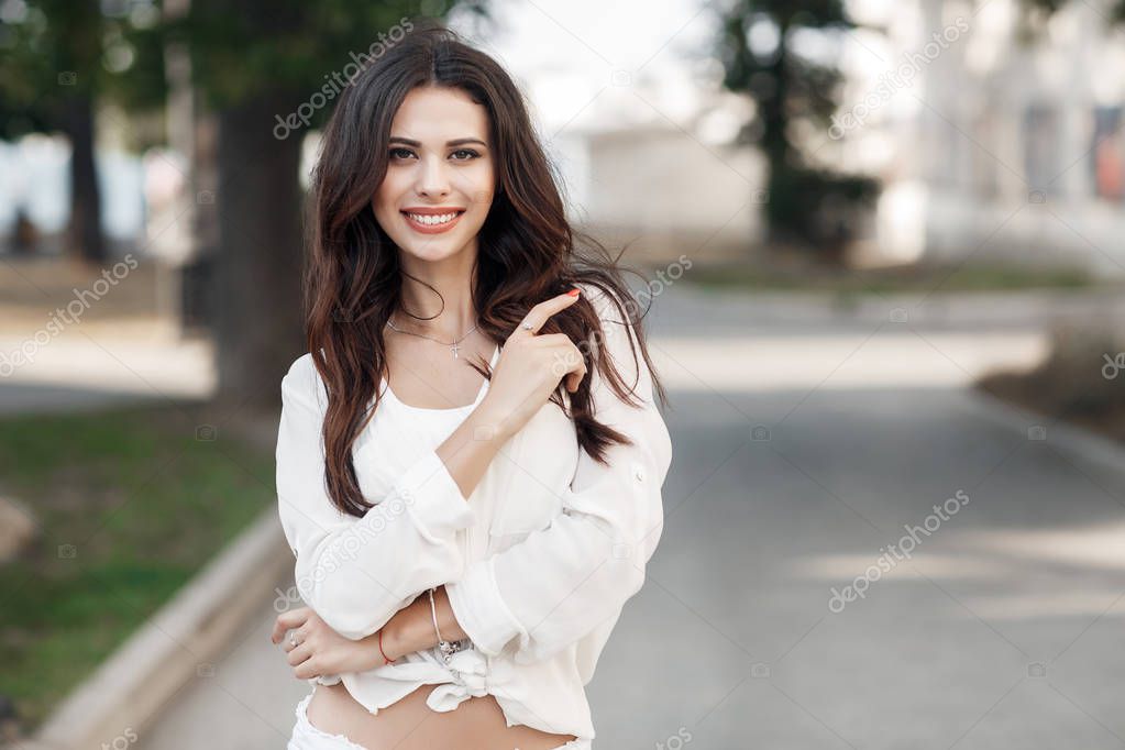 Beautiful Young Woman Enjoying nature Outdoor. Happy and Healthy Smiling brunette Girl with healthy smile relaxing in the Summer Park. Breathing fresh air. Sunny day. Health care concept