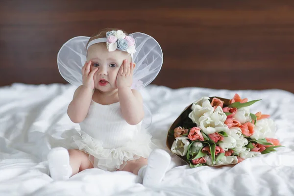 彼の後ろに天使の翼を持つ青い目の赤ちゃん 天使の翼を持つ赤ちゃん新生児 ブルースカイクラウドに座っている子供 女の子5 7ヶ月寝室の白いベッドに座って かわいい新生児の天使 — ストック写真