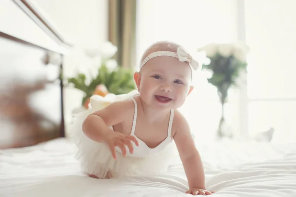 ベッドの上を這って笑う女の赤ちゃん 自宅で幸せな健康な小さな子供 日当たりの良い保育園の幼児 5ヶ月の子供は 雪の白いベッドに座って 一人で楽しんでいます — ストック写真