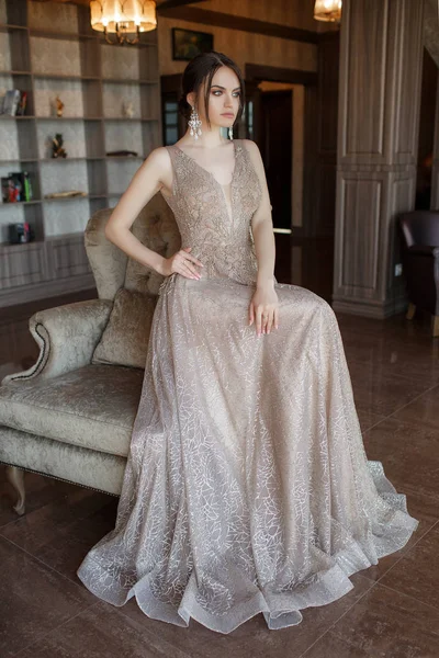 Beautiful woman in elegant evening dress. Brunette Girl with Long Healthy and Shiny  Hair. Beautiful young woman, model, in an evening dress indoors.A portrait of a beautiful elegant woman in the evening dress. Fashion, evening dresses for events.