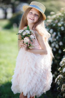 Portre güzel mutlu kız zevk kokusu bir çiçekli bahar çiçek Bahçe. Parlak ve şık yakınındaki çiçeği güzel kız gülümseyerek ağaç bahar bahçe beyaz çiçeklerle bush. Manzara. Şapkalı bir gülümseyen kız portresi bahar