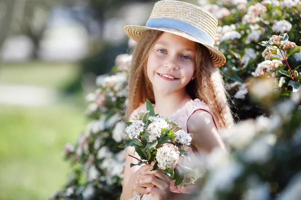 肖像画の美しい開花で幸せな女の子楽しんで香り春の咲く庭 明るくファッショナブルな美しい花近くの女の子の笑顔はブッシュ春の庭の白い花を持つツリーです 風景です 帽子の笑みを浮かべて少女の春の肖像画 — ストック写真