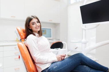 Diş kliniği. Resepsiyon, hastanın muayenesi. Diş bakımı. Gülümseyen genç kız, dişçisinde diş kontrolü yaptıktan sonra aynaya bakıyor. Dişçinin resepsiyonundaki güzel kız. Genç kadın bir diş hekimi tarafından diş muayenesi uğrar