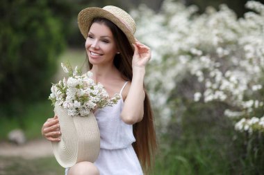 Romantik bir saç modeli ve profesyonel bir makyaj ile güzel kız bir bahçede beyaz renklerin bir koku sahiptir. Kız rüya görüyor. Parkta baharda güzel kız modelinin bir portresi
