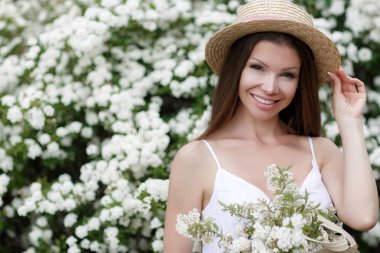 Romantik bir saç modeli ve profesyonel bir makyaj ile güzel kız bir bahçede beyaz renklerin bir koku sahiptir. Kız rüya görüyor. Parkta baharda güzel kız modelinin bir portresi