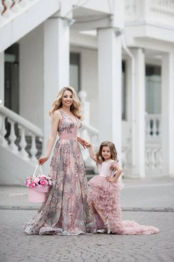 Güzel ince kadın ve küçük kızı, çiçekli şeftali ile bir saray sokakta, pembe renk güzel top Gowns giymiş, baharda açık havada eğlenmek. Sokakta güzel Abiye anne ve kızı