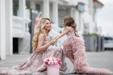 Güzel ince kadın ve küçük kızı, çiçekli şeftali ile bir saray sokakta, pembe renk güzel top Gowns giymiş, baharda açık havada eğlenmek. Sokakta güzel Abiye anne ve kızı