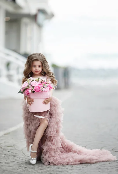 머리와 귀여운 분홍색 드레스를 분홍색 장미의 꽃다발과 테라스 아름다운 이브닝 — 스톡 사진