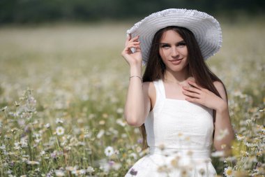 Güzel kız beyaz papatyalar bir alanda çiçek bir buket ile açık havada, doğanın tadını çıkarın. Beyaz elbiseli uzun saçlı güzel model çiçek açan çiçekler, Sun Light ile yaz alanında eğlenmek. Genç Mutlu Kadın bahar çayır, kırsal