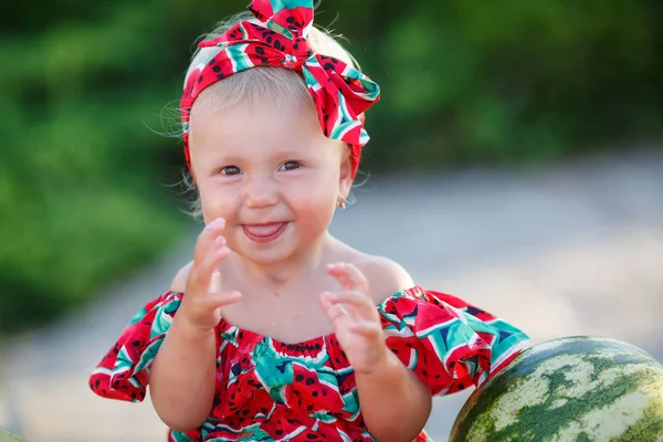 庭でスイカを食べる子供 子供たちは屋外で果物を食べる 子供のための健康的なスナック 庭で遊んでいる小さな女の子は スイカのスライスを持っています 子供は笑顔で果物を食べて楽しんでいます 屋外で熟した赤いスイカの背景に子供 — ストック写真