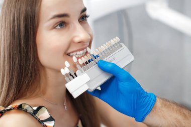 Diş sağlığı kliniği. Resepsiyon, hastanın muayenesi. Diş bakımı. Genç bir kadın diş hekimi tarafından muayene ediliyor. Mutlu hasta ve dişçi konsepti. Diş muayenesinde erkek dişçi kız hastayla konuşuyor. Güzel dişler.