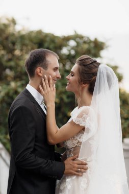 Düğün gününde gelin ve damat yazın şato bölgesinde dışarıda yürüyor. Gelinlik çifti, yeni evli bir kadın ve sevgiyle kucaklaşan bir erkek. İnsanlar mutlu ve gülümsüyor. Gelin, damadın ellerinde. Birbirlerine aşık mutlu çiftler.