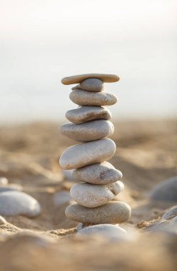 Kum üzerinde deniz taşları kulesi. Yaz ve gün batımı deniz arka planında. Kumsalda rahatlama ve meditasyon. Yüksek kalite fotoğraf